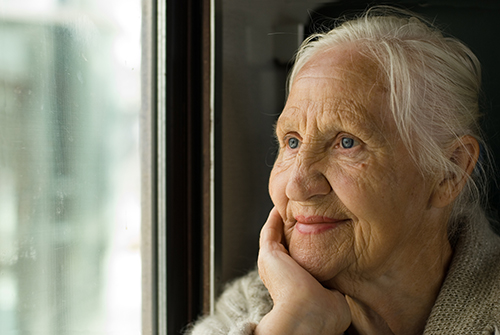 Woman with her hand resting in her hand gazing out of the window smiling